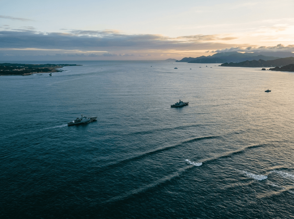 Several patrol boats traveling across coastal waters near mountainous islands